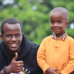 About Smiling adult and child in colorful outdoor portrait in Gitega, Burundi.