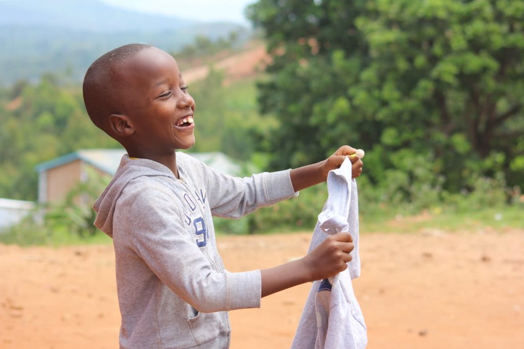 A happy young boy laughing and playing outside in Gitega, Burundi, on a sunny day.