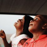 About Two joyful African children look upwards with anticipation, capturing a moment of wonder and curiosity.