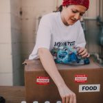 About A woman volunteer organizes bottled water for a food distribution event.